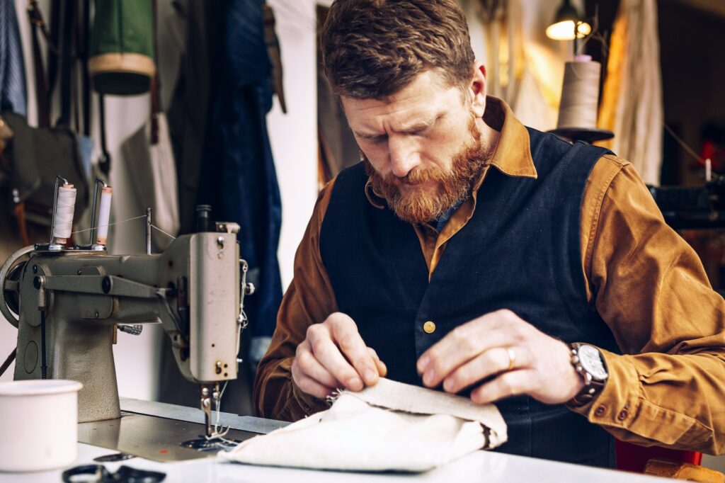Worker making bag at sewing table in workshop
